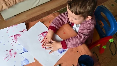 Top view of colored handprints on a sheet of paper. Boy draws color paints Stock Footage 172590730