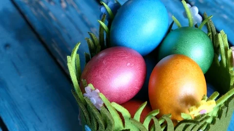 Top View Of Colorful Easter Eggs In A Grass Basket With Easter Rabbits On A Blue Vídeos de archivo 126589347