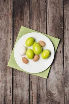 Top view of colorful Easter eggs on white plate and napkin on wooden table 库存照片