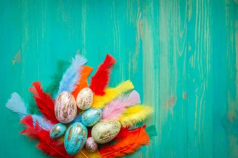 Top view of colorful Easter eggs and feathers on wooden background Stock Photos