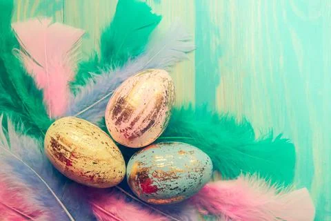 Top view of colorful Easter eggs and feathers on wooden background Stock Photos