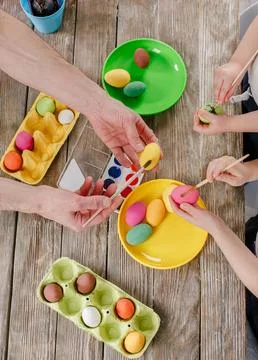 Top view of colorful Easter eggs, paints and brushes on wooden table with flo Stock Photos