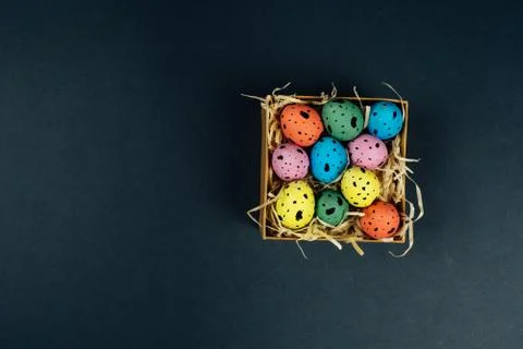 Top view with colorful painted Easter quail eggs in little box on black Stock Photos