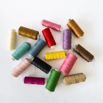 Top View of Colorful Sewing Thread Spools Arranged Randomly on White Backgrou Stock Photos