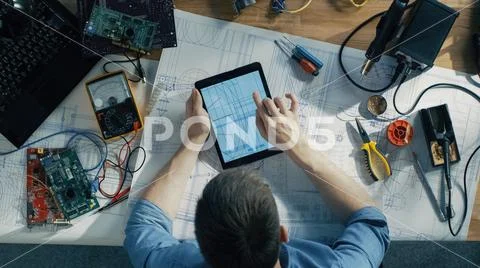 Top View of Competent IT Technician Working on Blueprints, He's Holding Tablet Stock Photos
