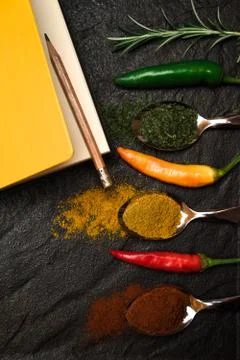 Top view on composition notebook for recipe and oriental spices in spoons and Stock Photos