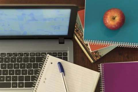 Top view of computer, books, notebook, pen and apple. Online homeschooling Stock Photos