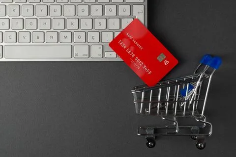 Top view of computer keyboard, credit card and mini market cart on dark gra.. Stock Photos