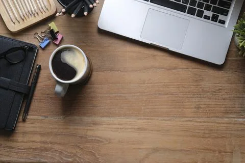 Top view computer laptop, stationery and coffee cup on wooden table. Stock Photos