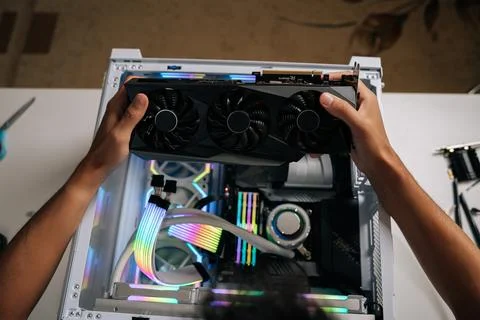 Top view of computer technician carefully inserting high-performance graphic Stock Photos