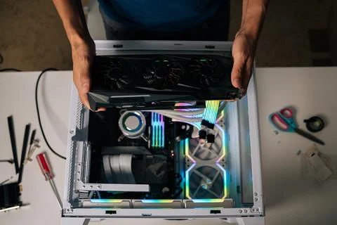 Top view of computer technician installing high-end graphic card into custom Stock Photos