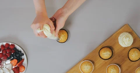 Top view of confectioner squeezes white cream on cupcake Stock Footage 129326056