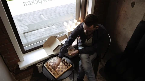 Top view of a contented handsome young man drinking whiskey and playing chess Stock Footage 112343844