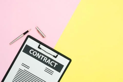 Top view of a contract document and a pen on pink and yellow pastel color. Stock Photos