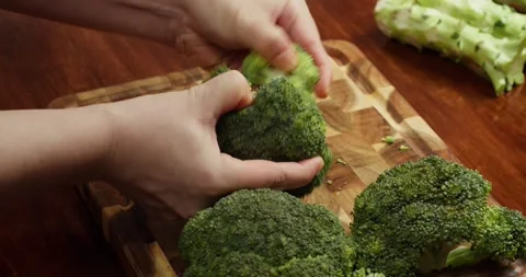 Top view Cook Breaking fresh broccoli into florets on a wooden cutting board. Stock Footage 319389014