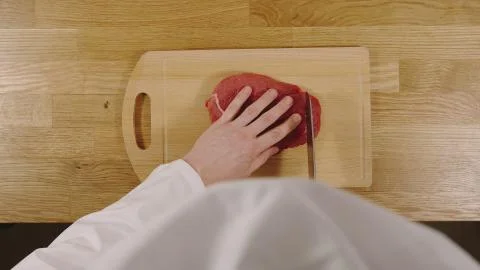 TOP VIEW: Cook cutting beef on a board Stock Photos