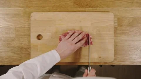 TOP VIEW: Cook cutting a pork on a cutting board Stock Photos