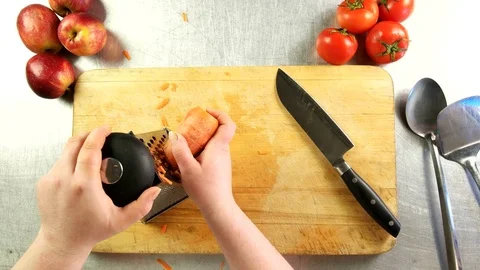 Top view the cook grates carrots on a grater Stock Footage 76095222