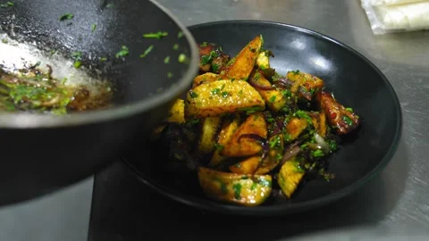Top view, cook putting baked potato wedges in pan on black plate Stock Footage 267297085