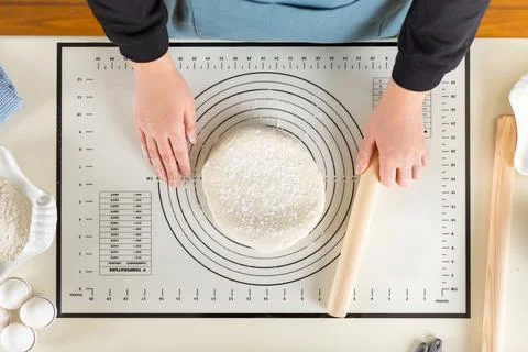 Top view of cooked wheat dough and hands of chef with rolling pin in hand on Stock Photos