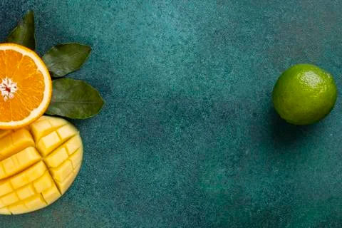 Top view  copy space  sliced mangoes with half an orange and bananas on a gre Stock-Fotos