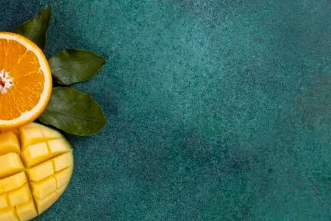 Top view  copy space  sliced mango with half an orange on a green background Stock Photos