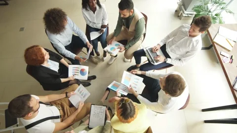 Top view of corporate workers in a circle comparing data from diagrams and Stock Footage 120663602