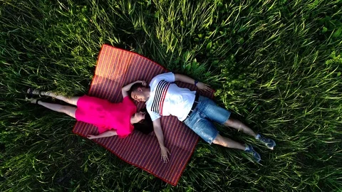 Top view of a couple in love lying on the grass and looking at each other. view Stock Footage 126485232
