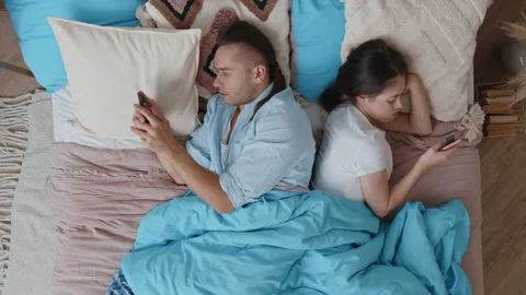 Top view of couple is lying in bed backs to each other and looking at their Stock Footage 167959673