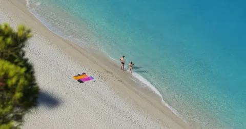 Top view of couple standing on beach with feet in the water waves Stock Footage 298924704