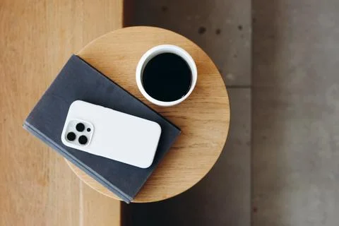 Top view of a cozy cafe table with a cup of coffee, book and a smartphone. Stock Photos