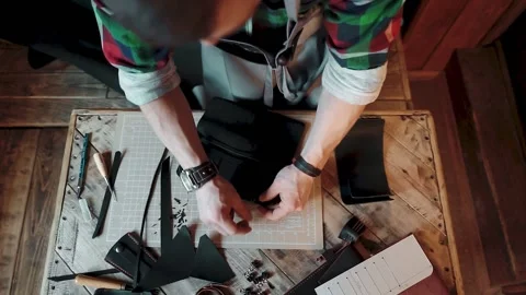 Top view of a craftsman creating a black leather wallet on wooden table Stockbeeldmateriaal 146352422