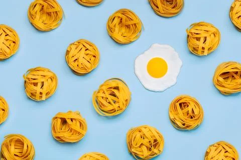 Top view of creative pattern made of raw tagliatelle nests pasta and a frie.. Stock Photos