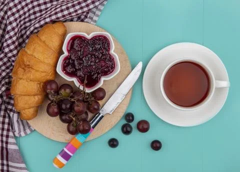 Top view of croissant and raspberry jam in bowl grape with knife on cutting.. Stock Photos