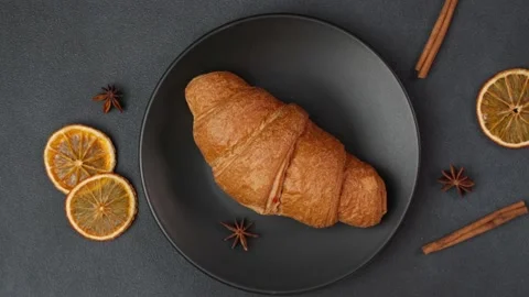 Top view of a Croissant Lying on a black Plate against a black background Video stock 237313451