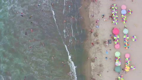 Top view of a crowded beach with coloful parasols lining the ocean Stock Footage 169904378