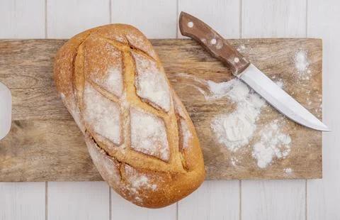 Top view of crusty bread with knife and flour on cutting board on wooden ba.. Foto stock