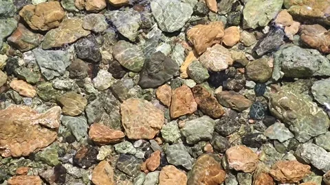 Top View of Crystal Clear Water Rippling Over Colorful Stones and Pebbles Stock Footage 327594623