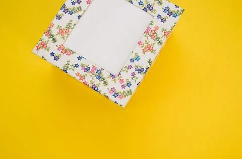 A top view of a cube cardboard box with flower patterns isolated in the yello Foto stock