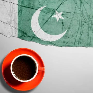 Top view of a cup of black coffee in an orange cup next to the Pakistan fla.. Fotos Stock