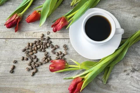 Top view of cup of coffee and beans and bouquet of red tulips. womens mothe.. Fotos Stock
