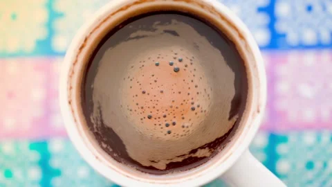 Top view of a cup of coffee on a colored background. Coffee foam swirls after Stock Footage 201300877