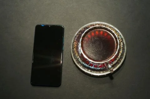 Top view of a cup of coffee, isolate on black background and a smartphone Stock Photos