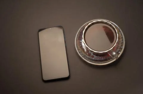 Top view of a cup of coffee, isolate on black background and a smartphone Stock Photos