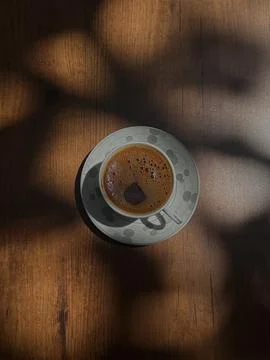Top view of a cup of coffee placed on a wooden table with warm natural sunl.. 스톡 사진