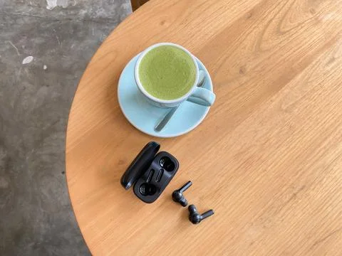 Top view a cup of green tea with A charging dock with TWS bluetooth headset o Stock Photos
