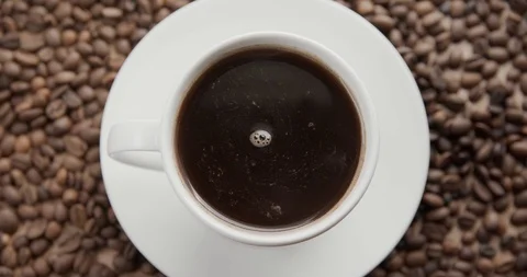 Top view of a cup of hot coffee on a dark background full of coffee beans. Stock Footage 115968183