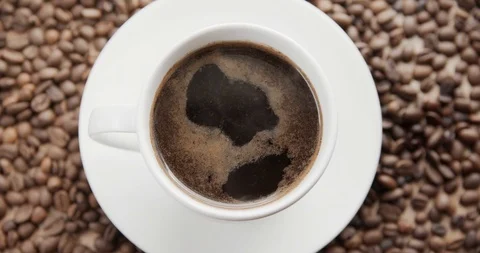 Top view of a cup of hot coffee on a dark background full of coffee beans. Stock Footage 115969882