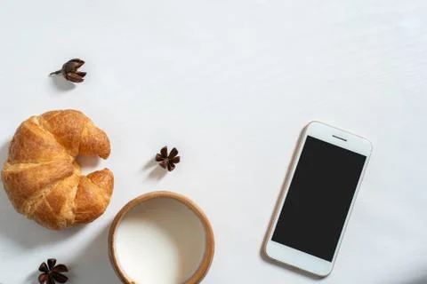 Top view of cup of milk, note book, croissant on wooden table Stock Photos