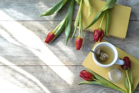 Top view of cup of tea and bouquet of red tulips, flowers, hot beverage and.. Stock Photos